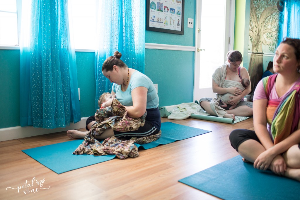 Two babies take a nursing break at a babywearing yoga class.