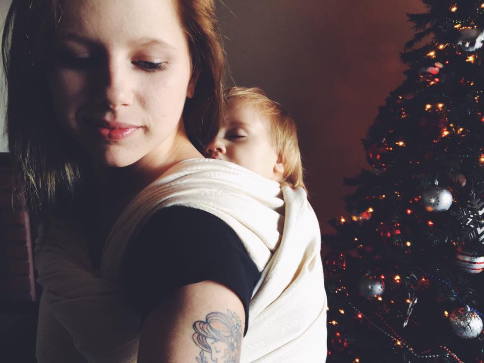 Baby sleeping in a back carry in front of the Christmas Tree